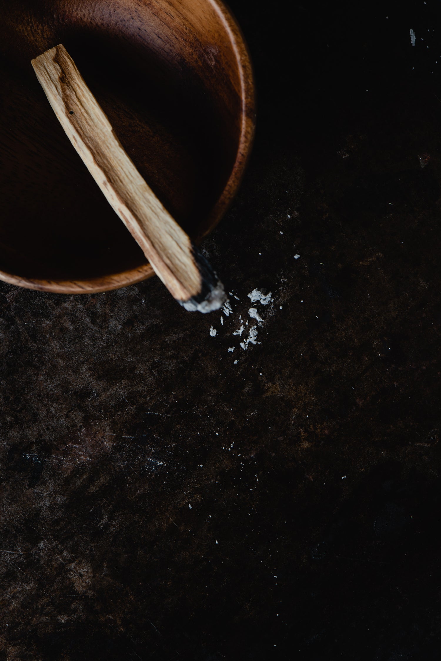 palo santo in wooden bowl on a dark table